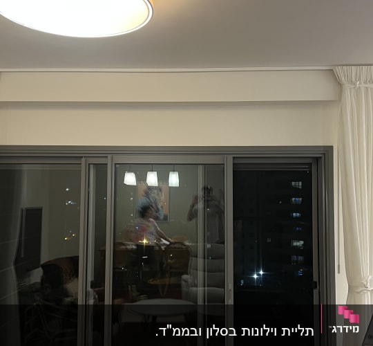 סולם מתכת ליד חלון עם וילונות לבנים